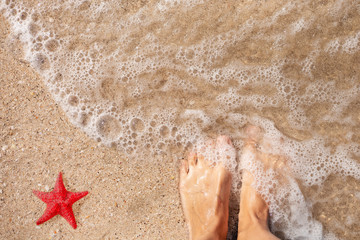 wet feet on the sand with sea water and red starfish top view