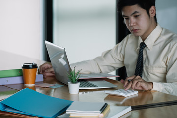 Businessman or accountant working on calculator to calculate business data, accountancy document and laptop computer at office, business concept