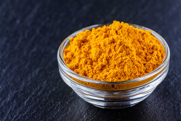 natural turmeric powder on a dark stone background