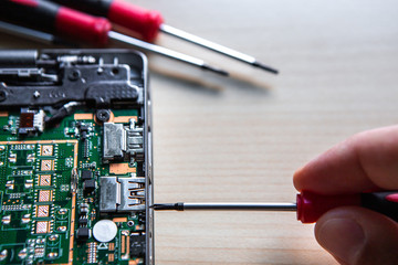 A screwdriver in the hand of a server disassembling a computer. The computer is broken and he hopes...
