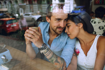 Fototapeta na wymiar Dreamy couple resting in cafe behind the window