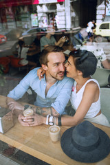 Fototapeta na wymiar Joyful couple sitting in cafe behind the window