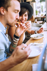 Man eating and smiling woman drinking in cafe