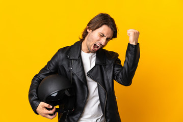 Man with a motorcycle helmet isolated on yellow background celebrating a victory