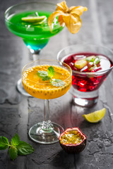 Assortment of different cocktails with fresh fruits and mint on black background.