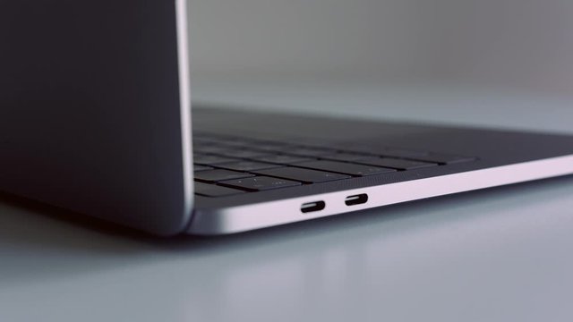 Close up side view of a new laptop with black keyboard on white background. Action. Presentation of new modern technological device.