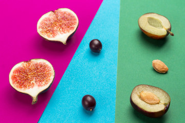Fruit on colored paper. Geometric flat composition of colorful paper and fruits: figs, grapes, plum.