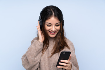 Young brunette woman over isolated blue background listening music with a mobile and singing