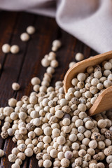 white peppercorns in wooden scoop on rustic background