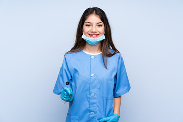 Woman dentist holding tools over isolated blue background