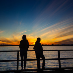The couple not talking on Jetty at Golden Sunset with Blue Sky and Water