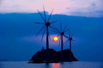Beautiful wind generator in the ocean at sunset.