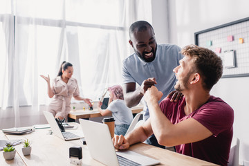 Selective focus of businessmen doing fist bump while working in office