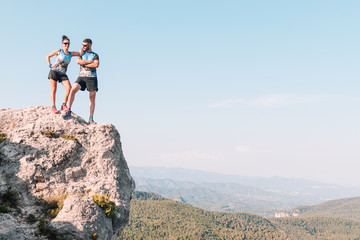 Fototapeta premium Man and woman mountain runners on top of some rocks observing the landscape.