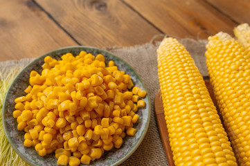 canned crumbly corn on a plate and peeled cobs on a wooden table