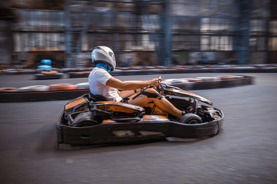 Male driving a kart through a turn on an indoor track