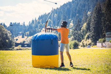 Teenage boy playing archery tag during summer
