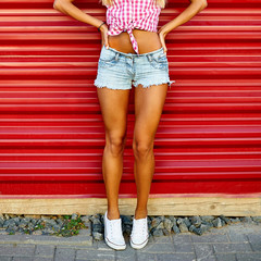 Woman legs in sneakers and jeans shorts. Outdoor street portrait