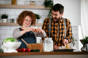 Fototapeta na wymiar Young couple making delicious food at home. Loving couple enjoying in the kitchen..