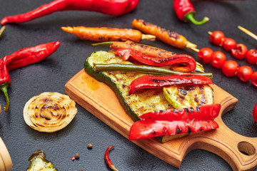 grilled vegetables on a wooden board on a black table