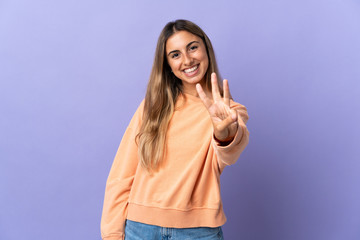 Young hispanic woman over isolated purple background happy and counting three with fingers