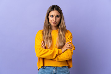 Young hispanic woman over isolated purple background with unhappy expression