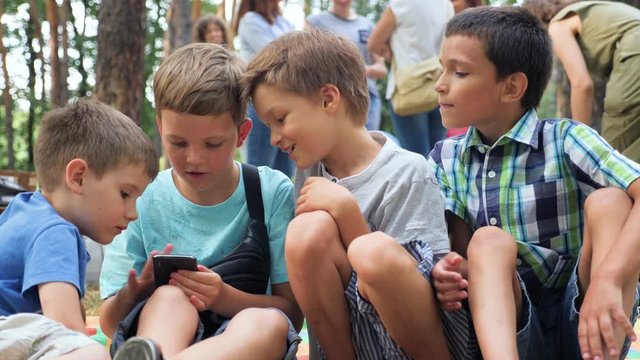 Three boys playing video game. Three brothers with gadget. Faces of three boys with phone outdoor. Leisure activity. Facial expression. Children interests. Positive emotions. Childhood concept.