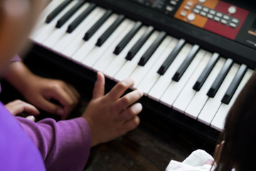Hands of kid on piano keyboard. Playing and practising at home.