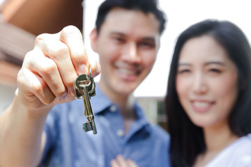 Asian married couple hold the keys of the new house. The concept of starting a happy family