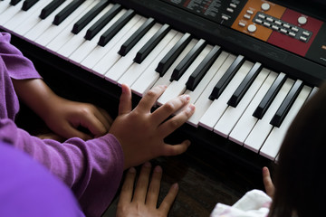 Hands of kid on piano keyboard. Playing and practising at home.