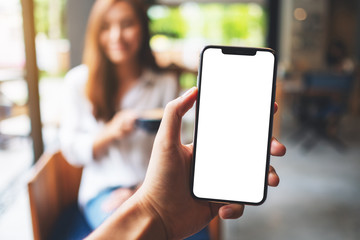 Mockup image of a man's hand holding mobile phone with blank white screen with woman drinking...