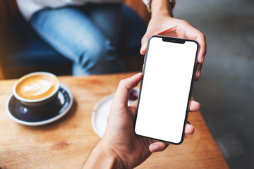 Mockup image of a woman holding and showing mobile phone with blank white desktop screen to someone
