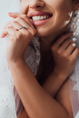 Obraz na płótnie Canvas Cropped view of young bride in jewelry ring touching lace veil