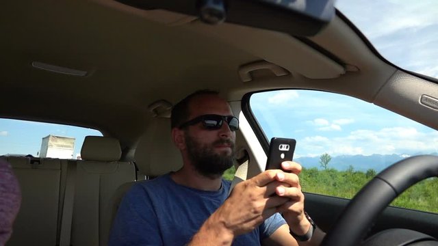 Man texting on smartphone, driving autonomous car on highway, slow motion