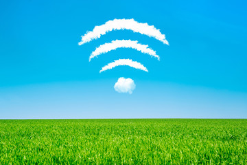 Clouds in the shape of a WiFi symbol on a blue sky and green meadow background. Public Free Wi-Fi...