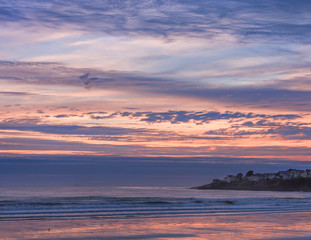 Early morning on the shores of the Atlantic Ocean. Beach at low tide and beautiful sky. Small houses of the town on the coast. USA. Maine.