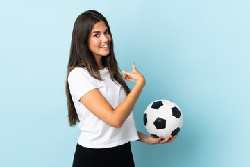 Young football player brazilian girl isolated on blue background pointing back