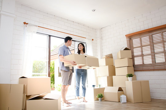 Asian couple buy a new house, hold a paper box to put things in. Move into a new house. Concept of starting a new life, creating a family. copy space