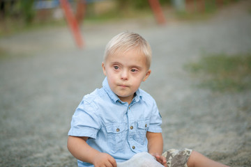 The daily life of a child with disabilities. A boy with Down syndrome sits on the ground and cries....