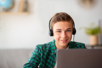 Portrait of schooler with headset sitting in front of laptop