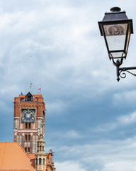 Fototapeta na wymiar Clock tower of town hall at Thorn market place. Main square in old town of Torun, birthplace of the astronomer Nicolaus Copernicus. Medieval gothic red brick vintage architecture.