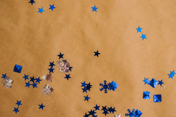 New year's confetti background in blue. Sequins of various shapes lie on Kraft paper. Festive background.