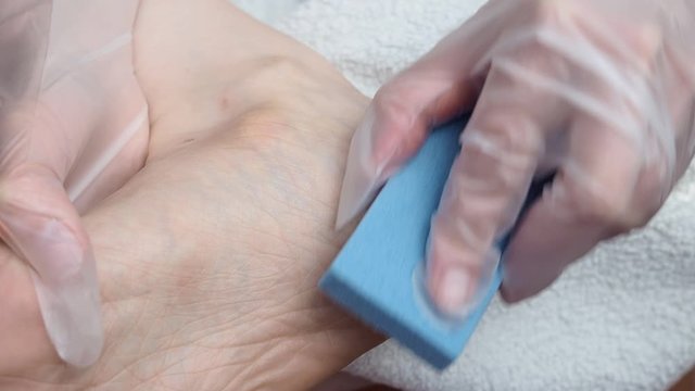 A woman peels her feet. Cleaning the skin of the feet with a cosmetic brush. Spa treatments at home.