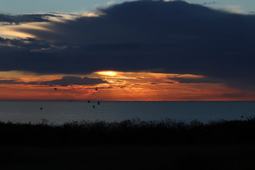 Hunstanton beach sun set over the sea ,glowing deep orange ball of fire 