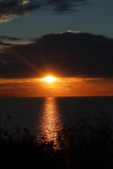 Obraz premium Hunstanton beach sun set over the sea ,glowing deep orange ball of fire 