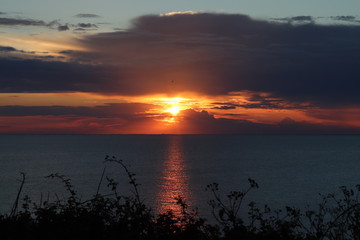 Hunstanton beach sun set over the sea ,glowing deep orange ball of fire 