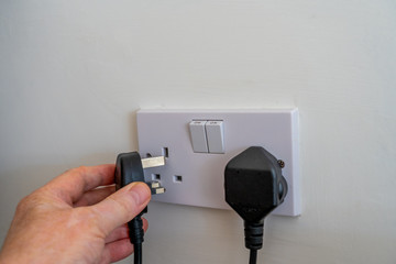 Selected Focus Plugging in a United Kingdom ( British) three pin fused plug into a double wall socket connecting an appliance to electrical power 240v