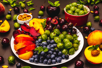 Assorted fresh berries of a cherry, gooseberry, blueberries, slices of ripe peach, plum and...