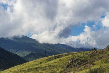 Wooden poles of power lines stand on the hills in the countryside. Travel the Altai year during the summer months.
