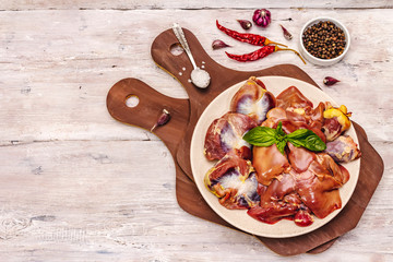 Fresh raw chicken offal: heart, liver, stomach with dry spices, sea salt, chili pepper on wooden table